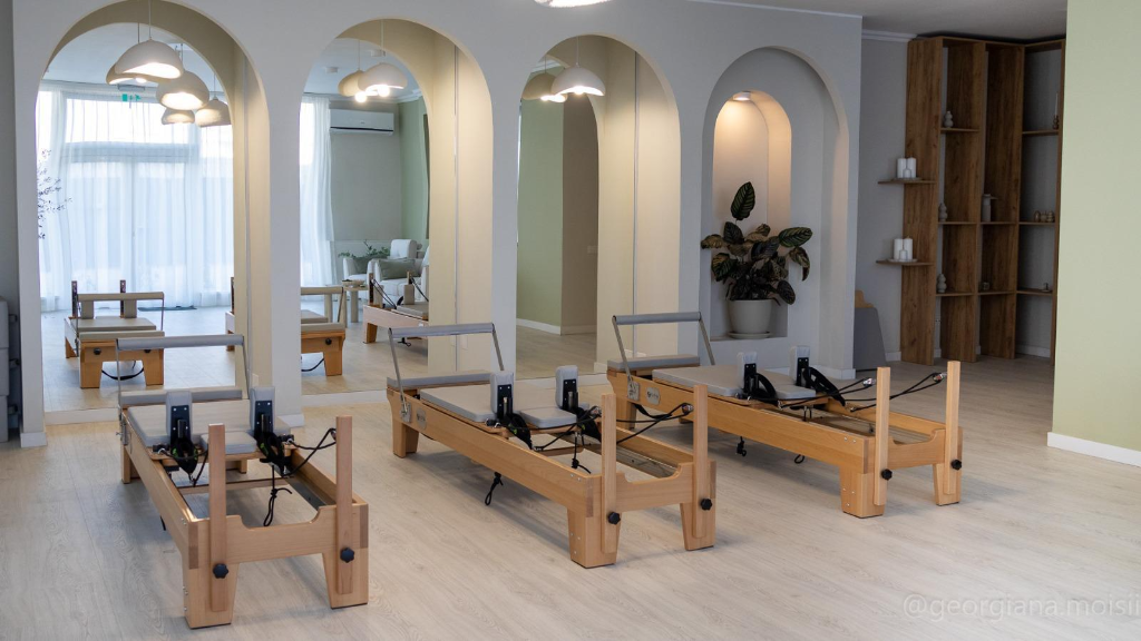 Sală Pilates Reformer cu aparate Alpha din lemn și arcade scandinave la Bloom Studio Cluj-Napoca